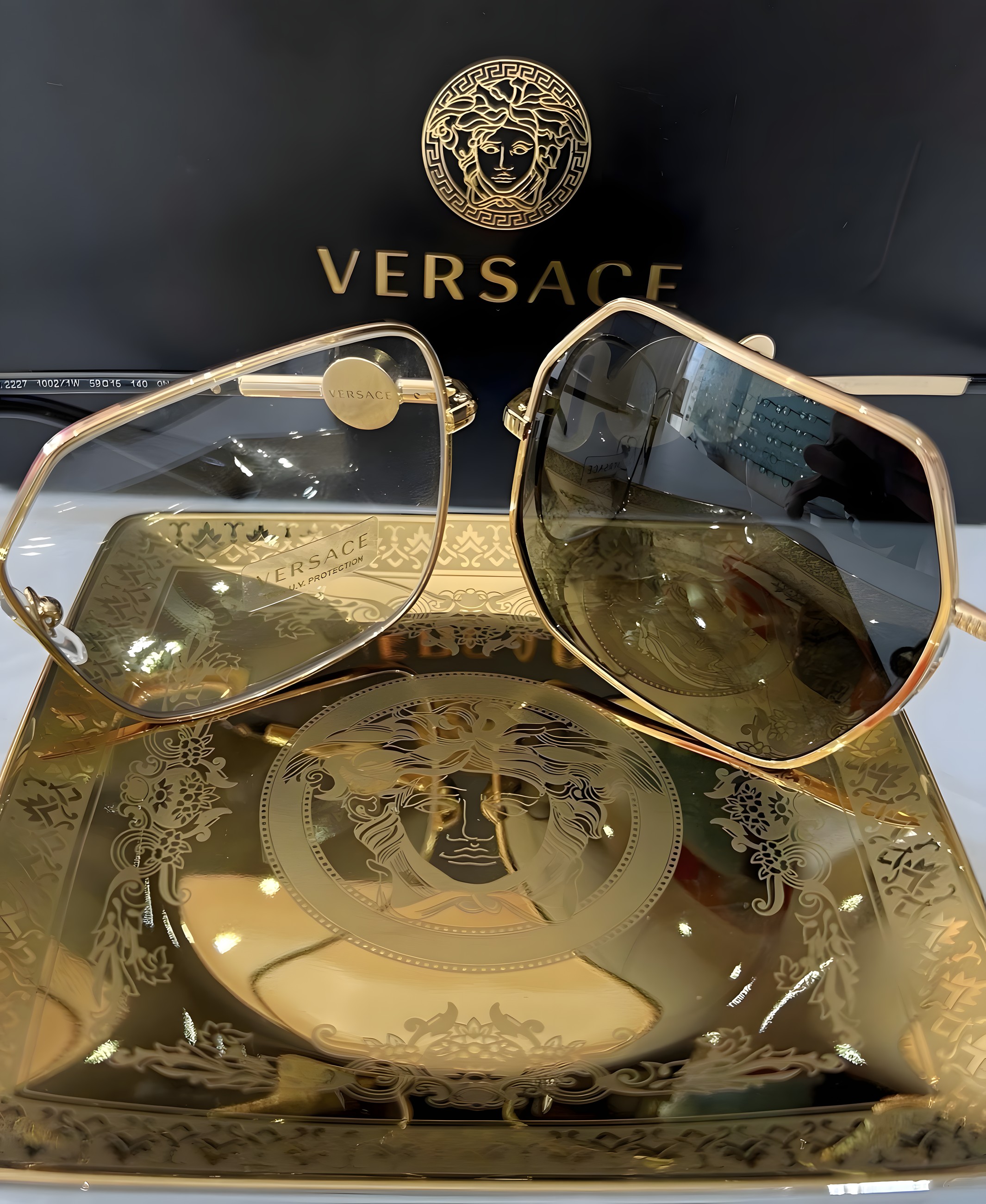 Gold Versace sunglasses resting on a Versace box